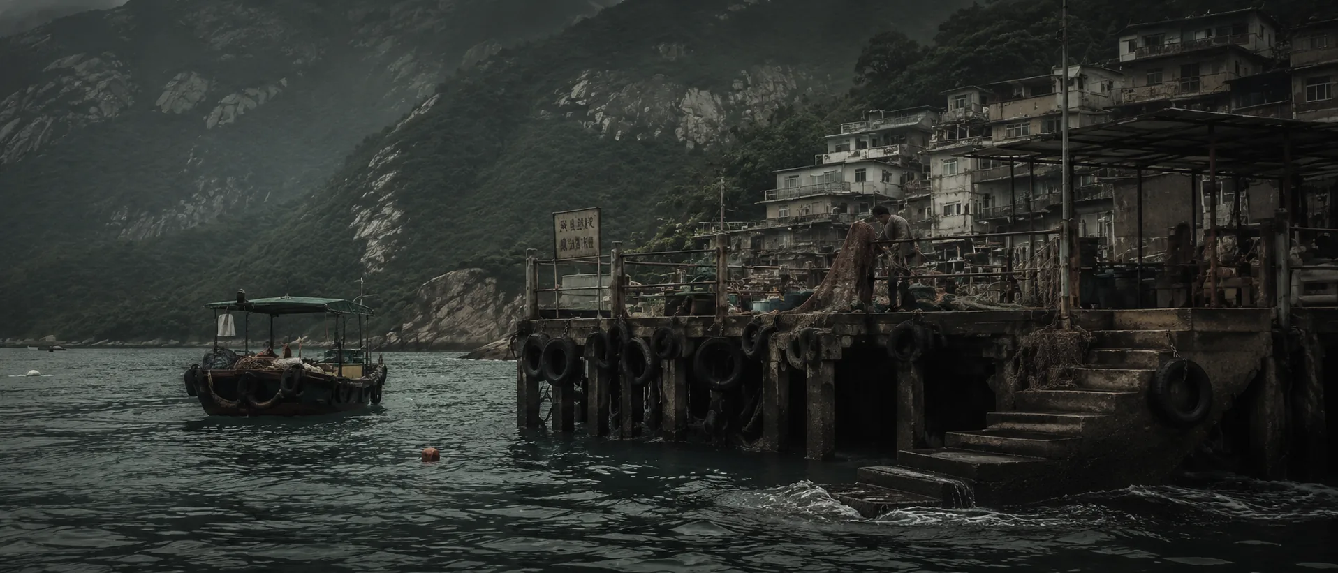A village pier of tyres and drying nets with a working boat alongside, a wooded ridge behind and no skyline anywhere in frame